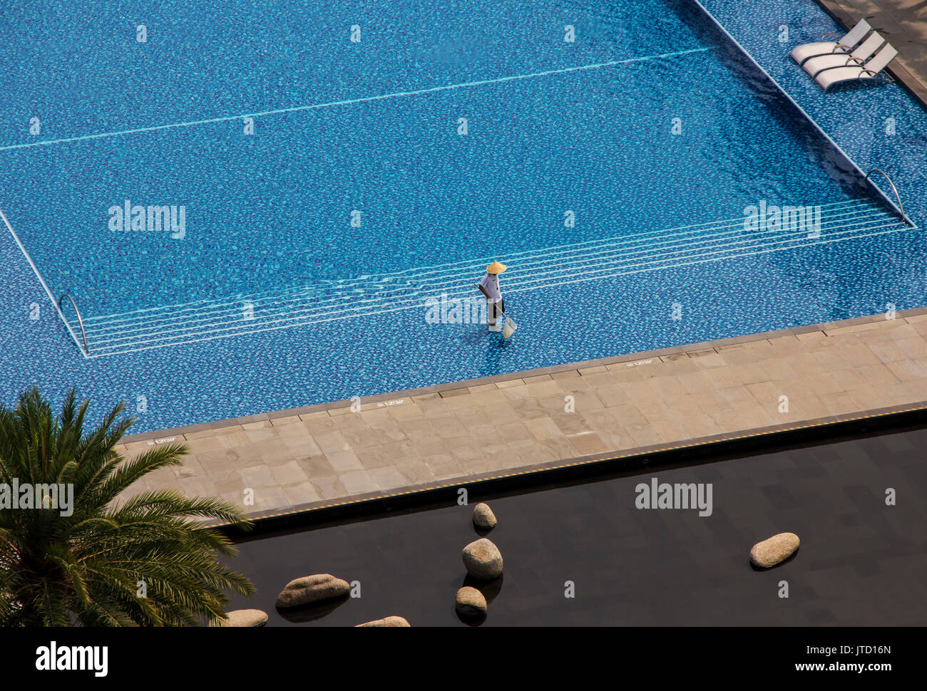 L'uomo la pulizia piscina scoperta in un hotel tropicale Foto Stock