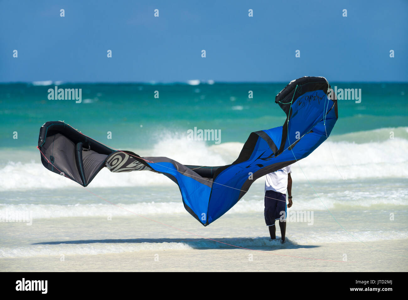 Kite surf kite sulla spiaggia con uomo locale tenendolo, Diani, Kenya Foto Stock