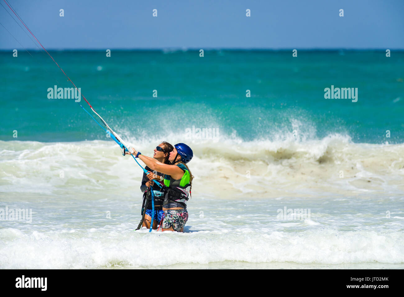 Kite surfer con tutor essendo mostrata come tenere il kite come stanno Nello shallow surf acqua, Diani, Kenya Foto Stock