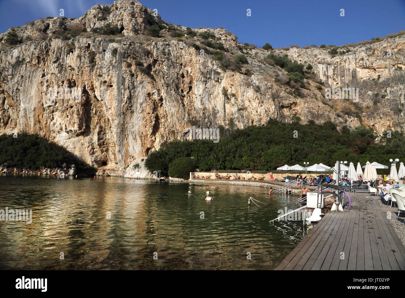 Vouliagmeni Atene Grecia turisti che nuotano nel lago Vouliagmeni una spa naturale - una volta era una caverna ma il tetto della grotta è caduto a causa dell'erosione del Foto Stock
