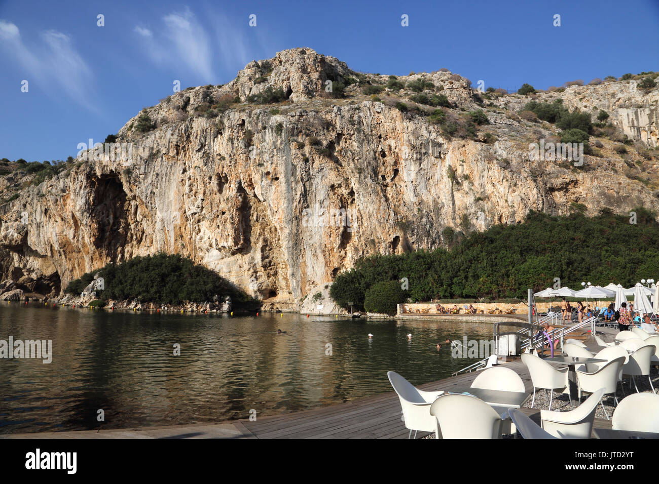 Vouliagmeni Atene Grecia turisti che nuotano nel lago Vouliagmeni una spa naturale - una volta era una caverna ma il tetto della grotta è caduto a causa dell'erosione del Foto Stock