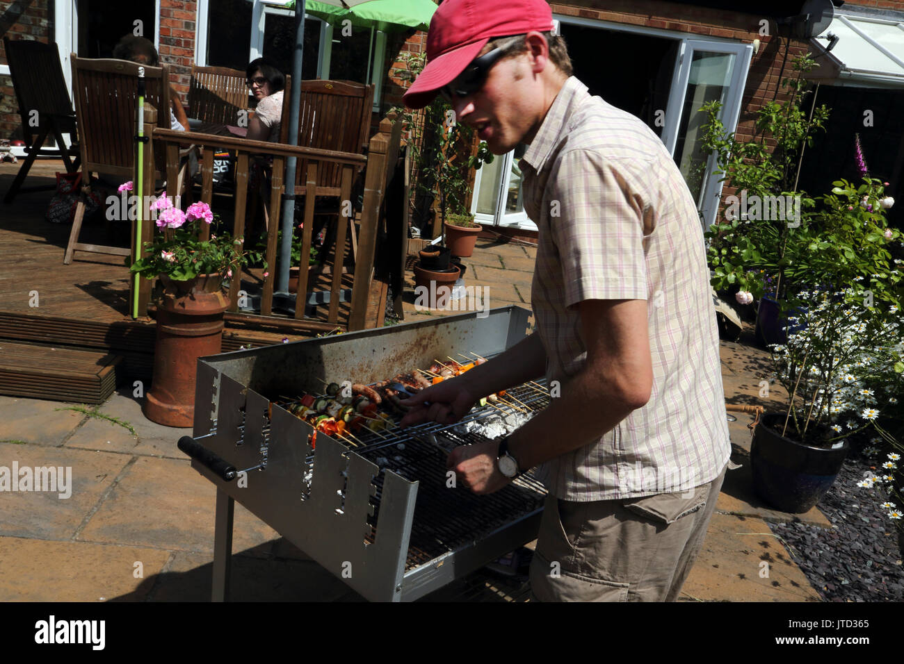 L'uomo la cottura a un barbecue in giardino durante i mesi estivi Birmingham West Midlands England Foto Stock