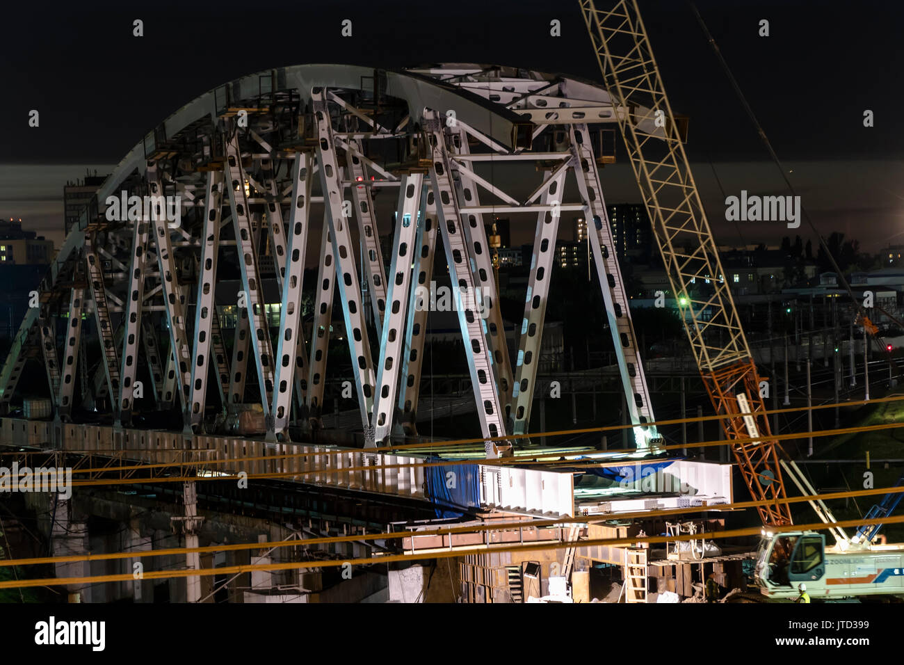 La costruzione di un ponte in acciaio di notte e la circolazione di treni su un nodo ferroviario Foto Stock