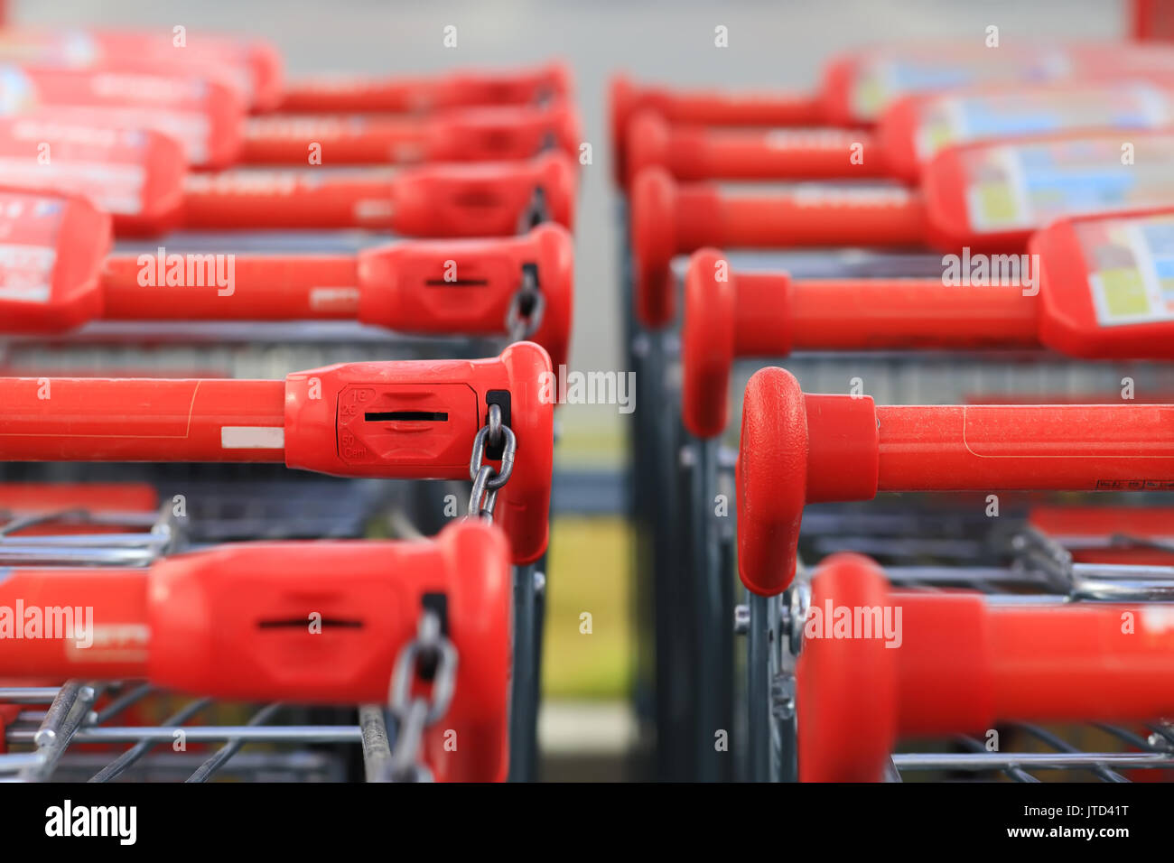 Maniglie rosse di carrelli di shopping in piedi in fila. Carrello spesa gestisce close-up. Foto Stock