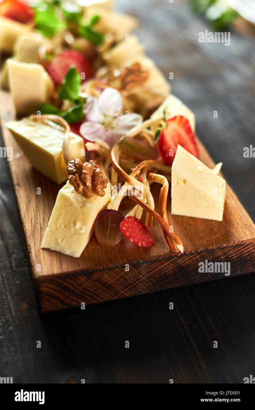 Pezzi di formaggio su una scheda con verdure hd Foto Stock