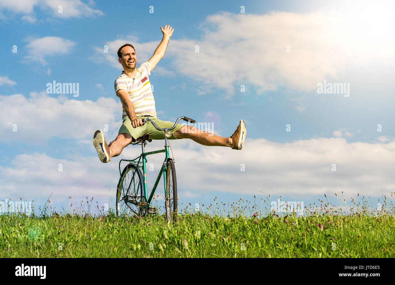 Felice l'uomo vincente sulla bicicletta. gambe e braccia sollevate verso l'alto. Foto Stock