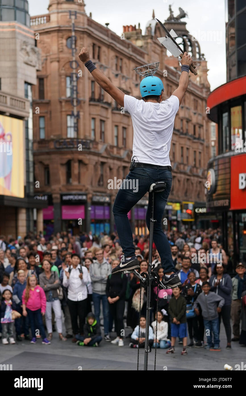 Un juggling unicyclist eseguendo per la folla in Leicester Square a Londra. Da una serie di quadri di artisti di strada a Londra, Regno Unito. Data foto: T Foto Stock