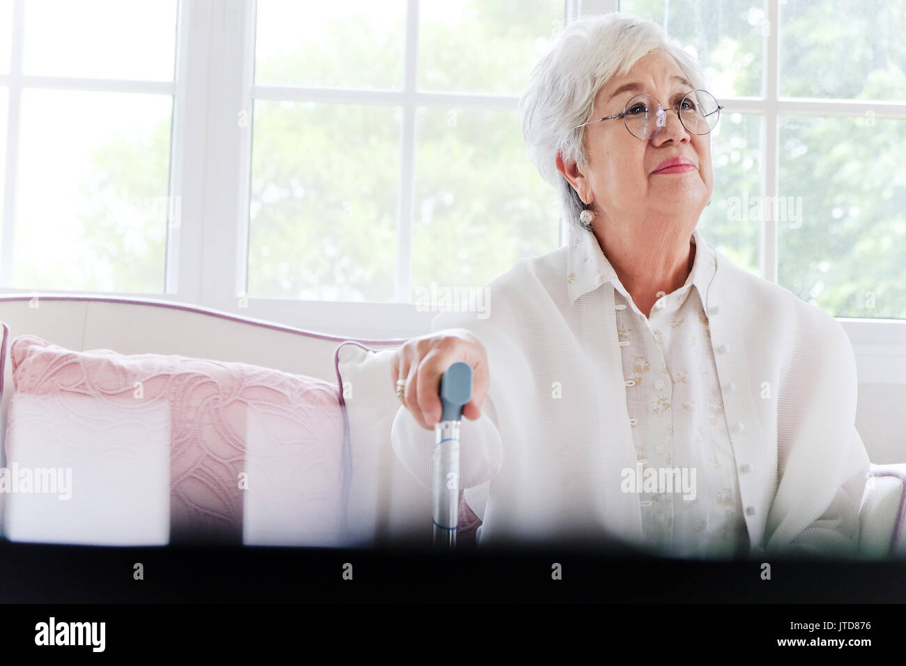 Senior ritratto di donna, senior donna seduta da sola su un divano a casa in un solitario dell'umore. Foto Stock