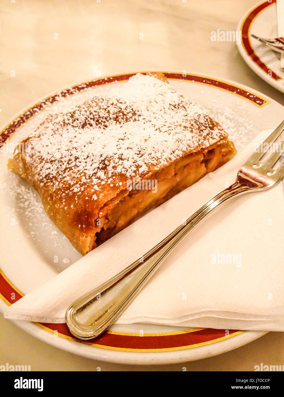 Strudel di mele e rabboccato con polvere di zucchero sulla piastra bianca e lo sfondo. Foto Stock
