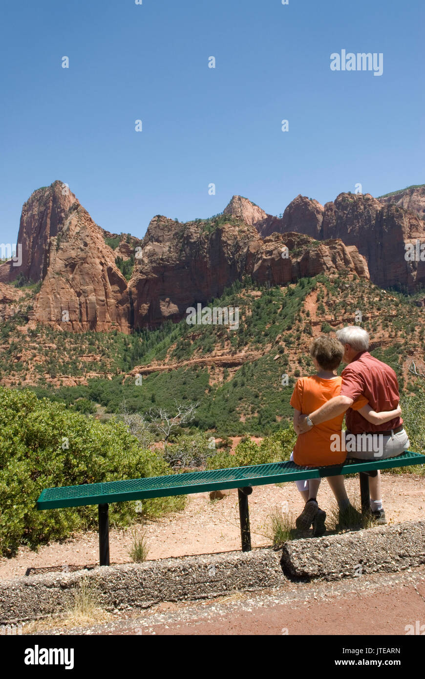 Coppia caucasica Senior (60-70 anni) seduta su una panchina con armi intorno a un altro ai Kolob Canyons allo Zion National Park Springdale Utah USA. Foto Stock