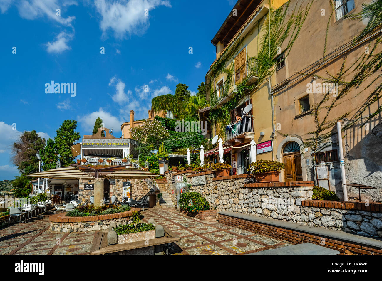 Piccolo quadrato a Taormina Italia sull'isola di Sicilia con un ristorante e un appartamento con una donna a stirare sul balcone Foto Stock