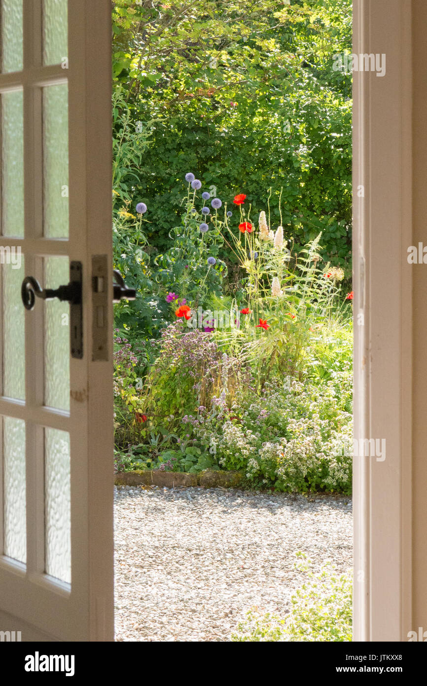 La porta anteriore di apertura al colorato cottage in stile giardino frontale in estate Foto Stock