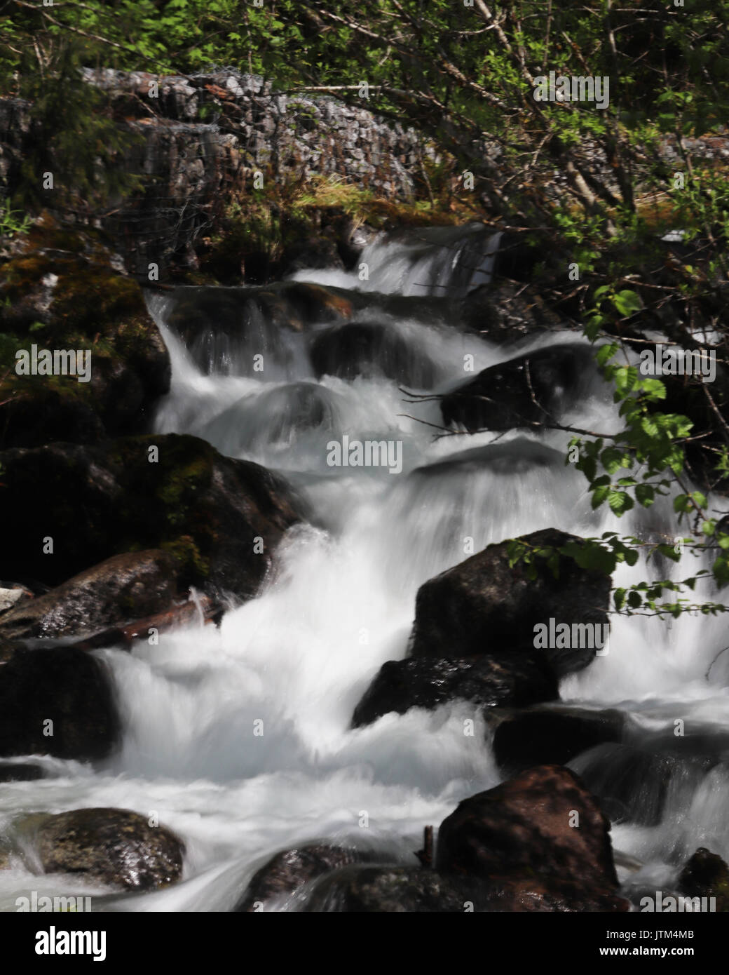 Una piccola cascata come fiume scorre verso il basso versante Foto Stock