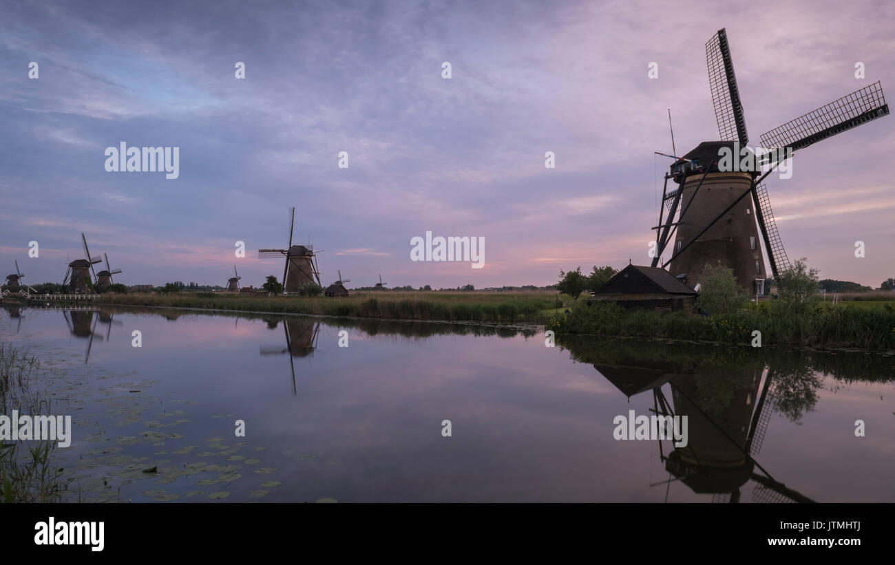 Tramonto a pittoreschi mulini a vento lungo l'acqua a Kinderdijk nei Paesi Bassi. Foto Stock