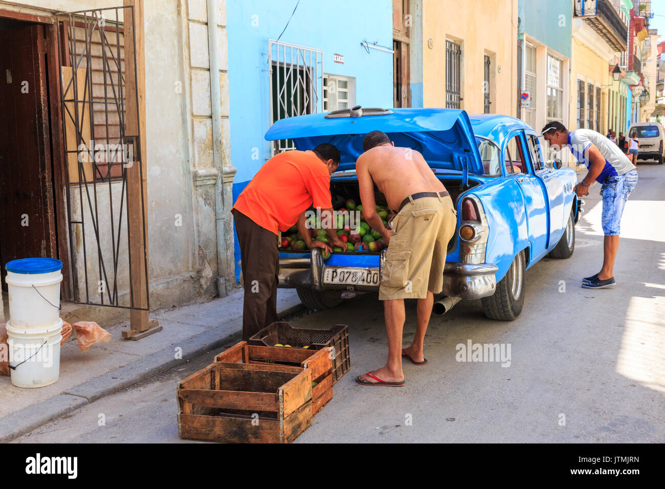 Cubano vita di strada - frutta fresca viene scaricato da un auto classica per la vendita a l'Avana vecchia scena di strada, Cuba Foto Stock