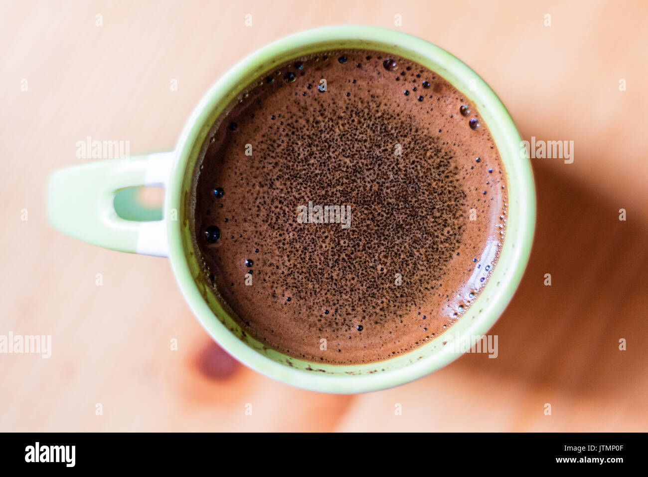 La tazza piena di caffè nero, vista dalla parte superiore verso il basso. Profondità di campo ridotta, scrivania è liscia. Molto bello e colorato immagine. Foto Stock