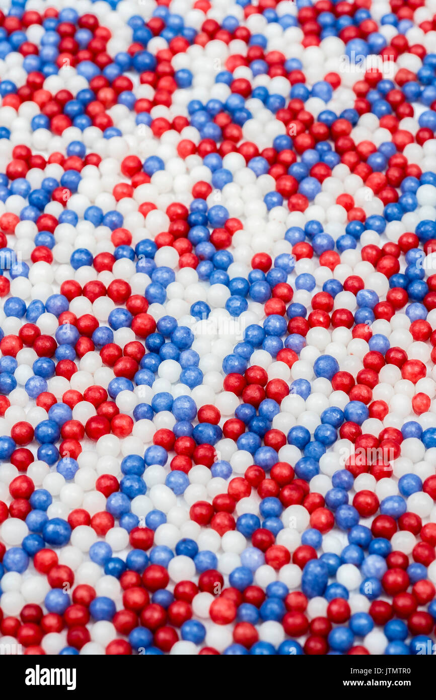 Micro-foto di rosso, bianco e blu di perle di zucchero in un ordine casuale. Metafora di settori di mercato, segmentazione, zucchero, fiscale UE quote di produzione di zucchero, dolce. Foto Stock