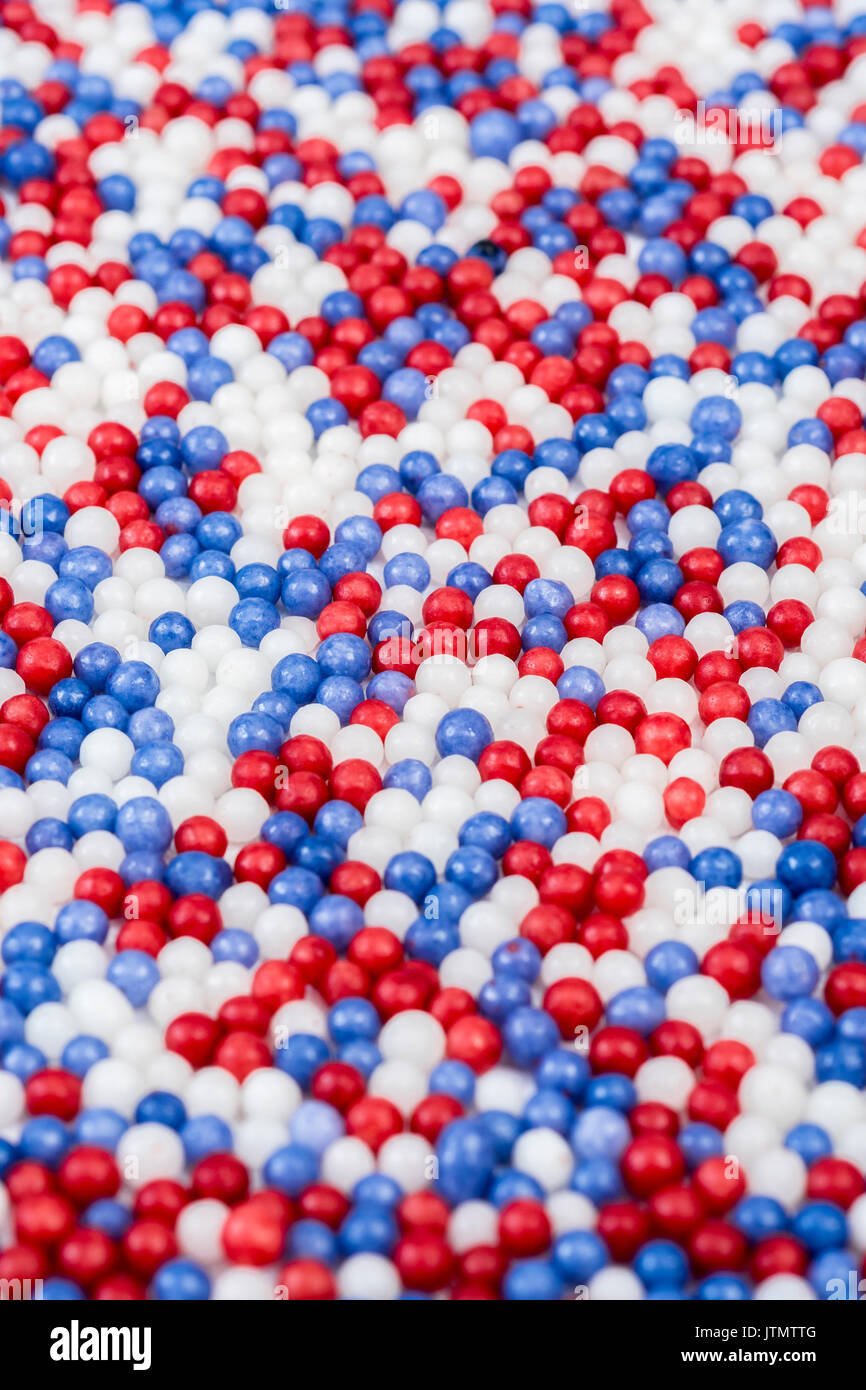 Micro-foto di rosso, bianco e blu di perle di zucchero in un ordine casuale. Metafora di settori di mercato, segmentazione, zucchero, fiscale UE quote di produzione di zucchero, dolce. Foto Stock