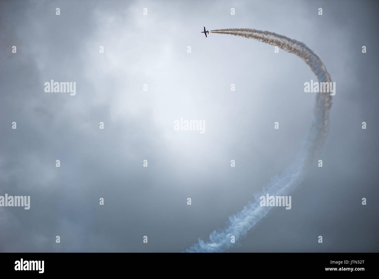 Jet aereo che effettua una curva con il fumo bianco contro un cielo scuro Foto Stock