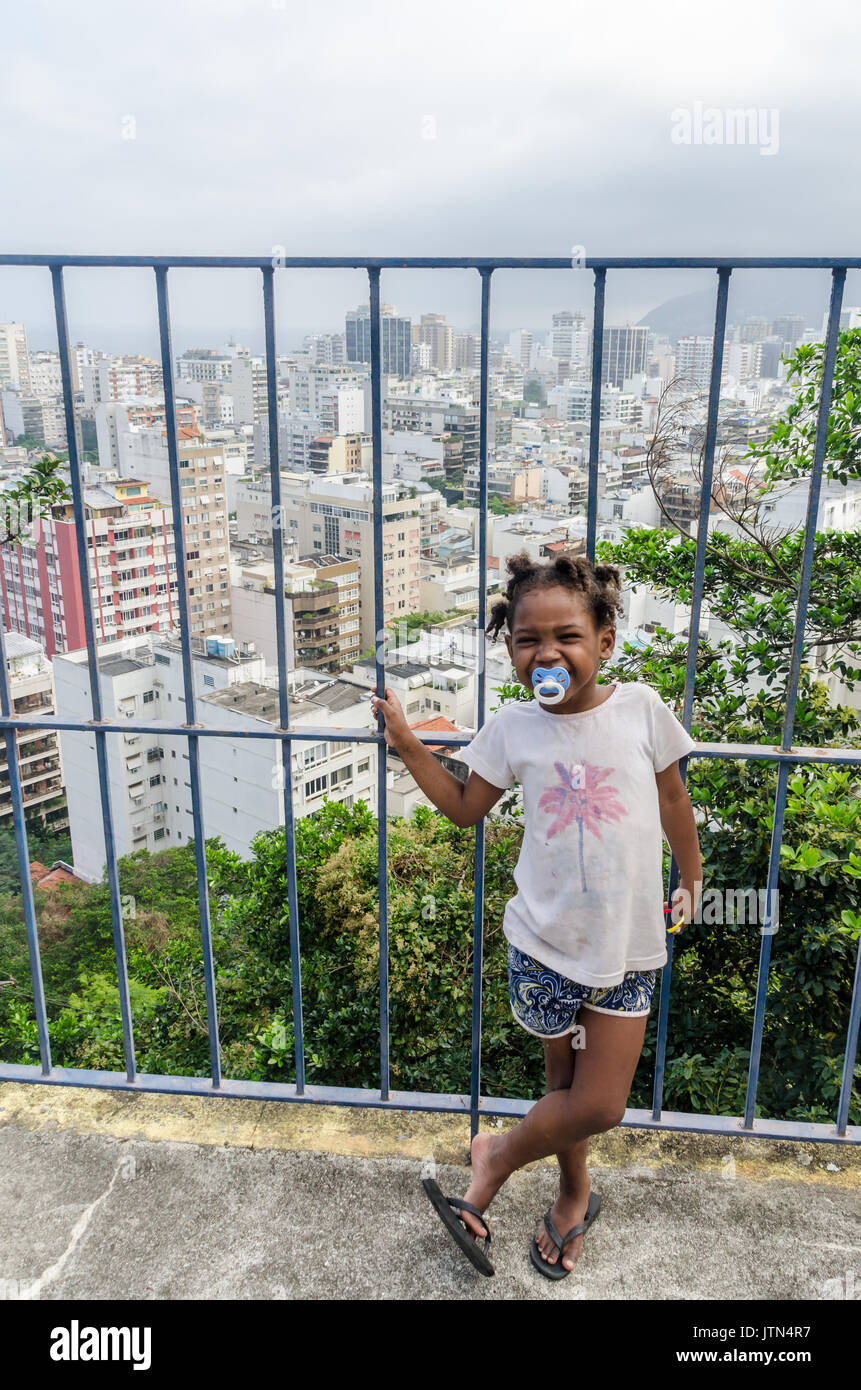 Una ragazza (4-6) sorrisi con Ipanema, a Rio de Janeiro sullo sfondo. Un messaggio scritto su una ragazza del braccio che si traduce in "mi manchi mamma". Prese a Cantagalo Foto Stock