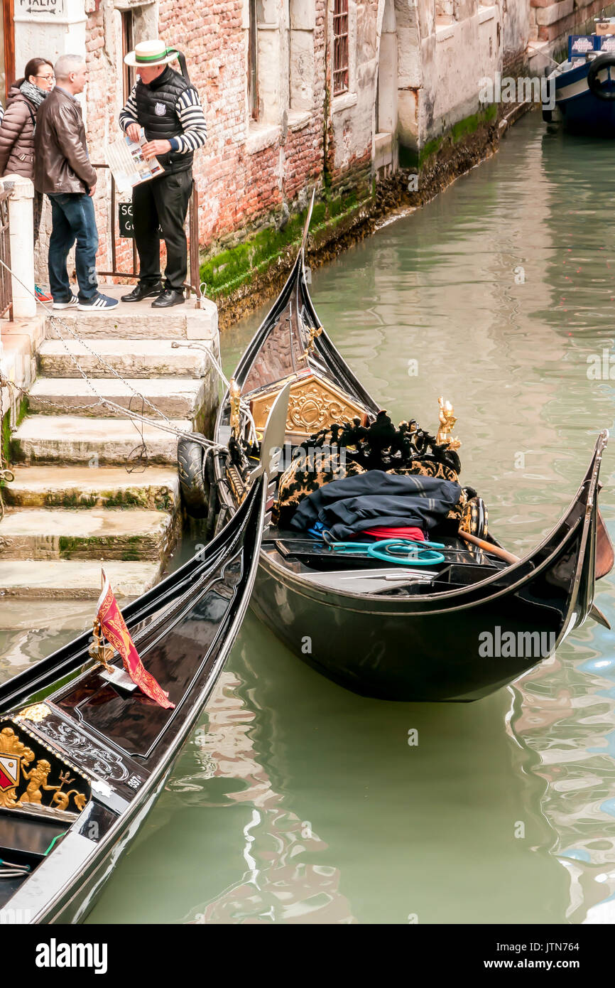 Due Gondolieri dalla loro gondole a passi in un canale veneziano. Foto Stock