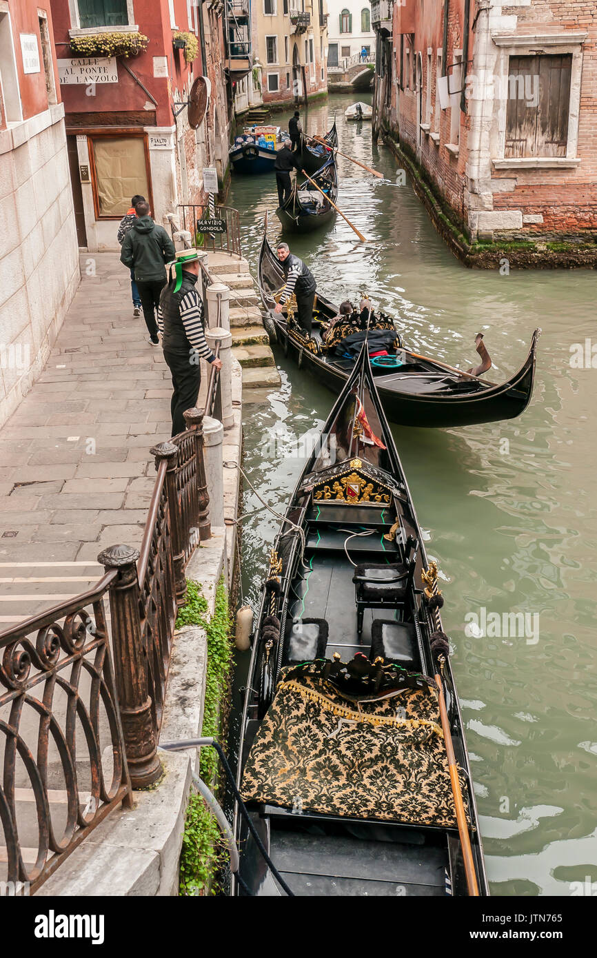 Due Gondolieri dalla loro gondole a passi in un canale veneziano. Foto Stock