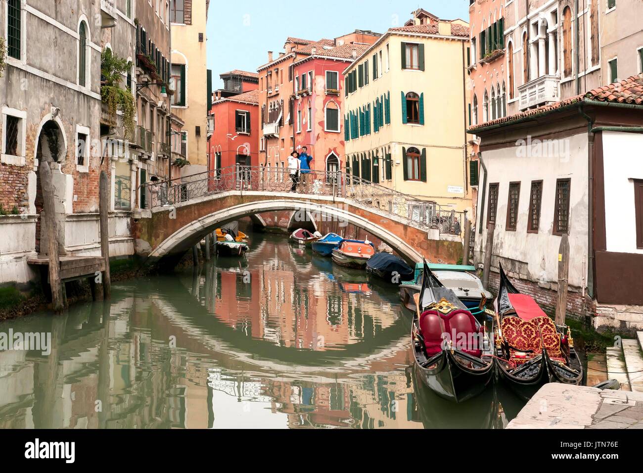 Due gondole di un canale veneziano con un ponte tradizionale in background Foto Stock