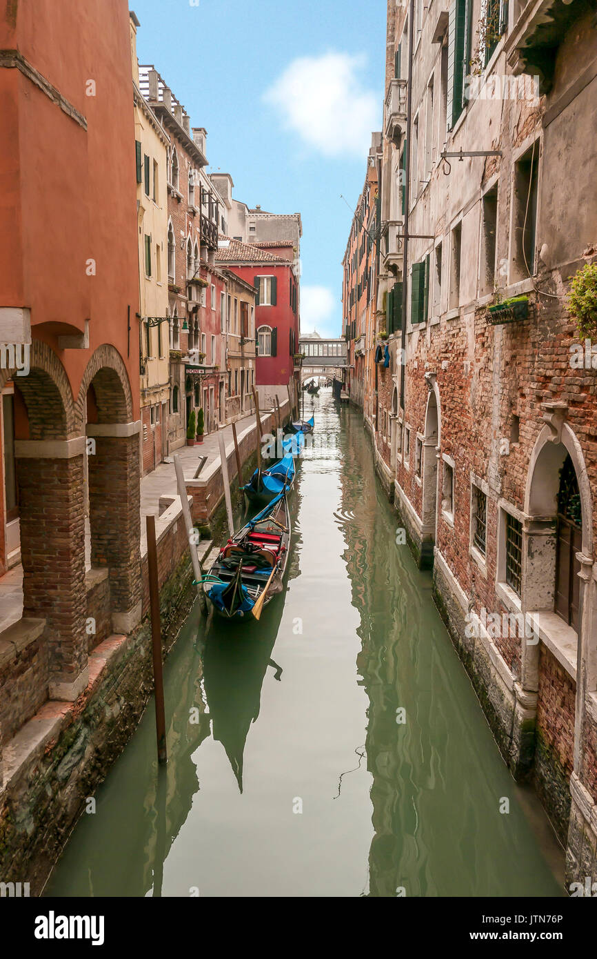Una gondola in un canale veneziano circondato da vecchi edifici storici. Foto Stock