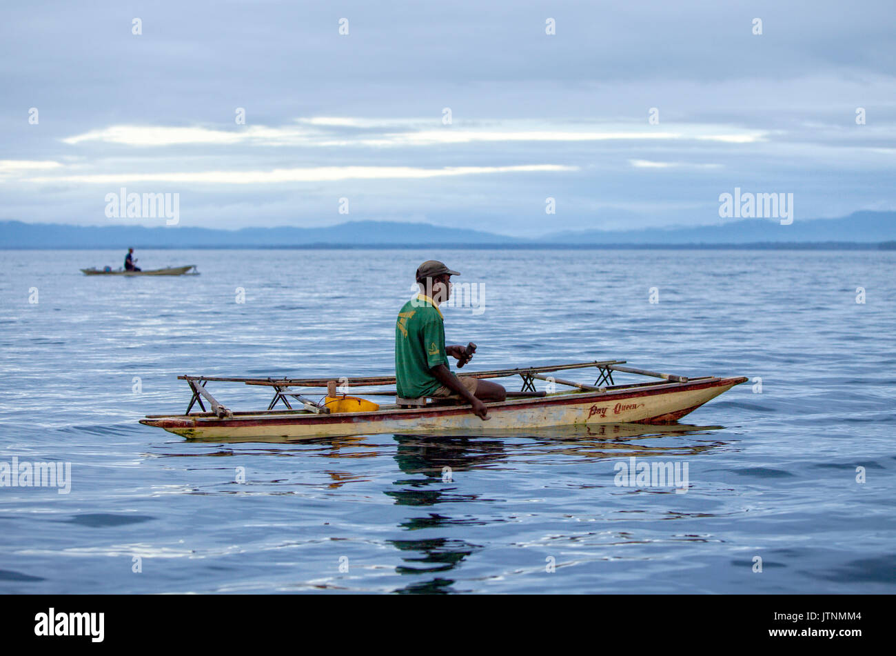 La mattina presto i pescatori in canoa outrigger nella baia di Alotau. Alotau è la capitale di Milne Bay Provincia, una provincia di Papua Nuova Guinea. La città si trova all'interno della zona in cui l'invasore esercito giapponese subito il loro primo terra sconfitta nella Guerra del Pacifico nel 1942, prima dell'Kokoda via battaglia. Un parco memoriale presso la vecchia battaglia sito commemora l'evento. Alotau divenne la capitale provinciale nel 1969 dopo che è stato spostato da Samarai. Alotau è il gateway per la baia di Milne Provincia che contiene alcune delle più remote isole europee nel mondo. Rinomata per Foto Stock