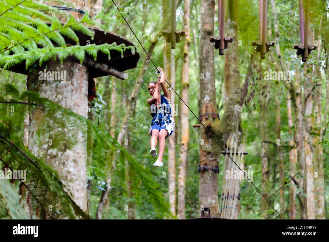 Una ragazza scende una zipline in un Treetop Adventure Park, Bali, Indonesia Foto Stock