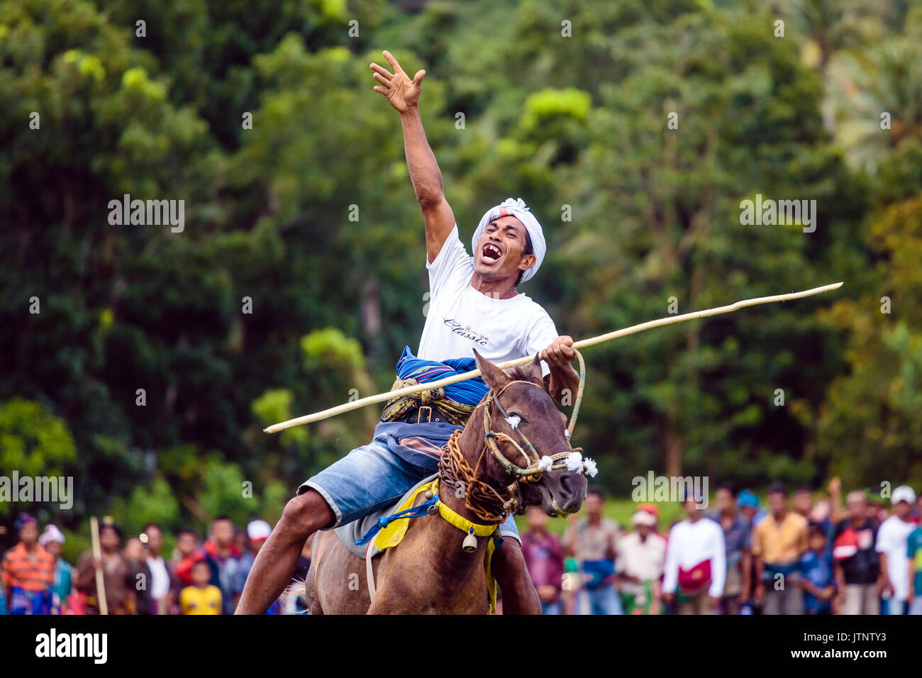L'uomo alzando la mano e a cavallo con lancia a Pasola Festival, isola di Sumba, Indonesia Foto Stock