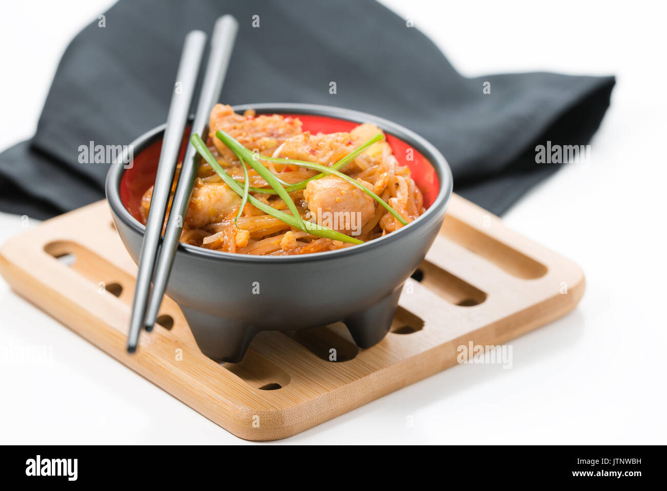 Ciotola di delizioso pollo pad thai su un bambù trivet. Foto Stock