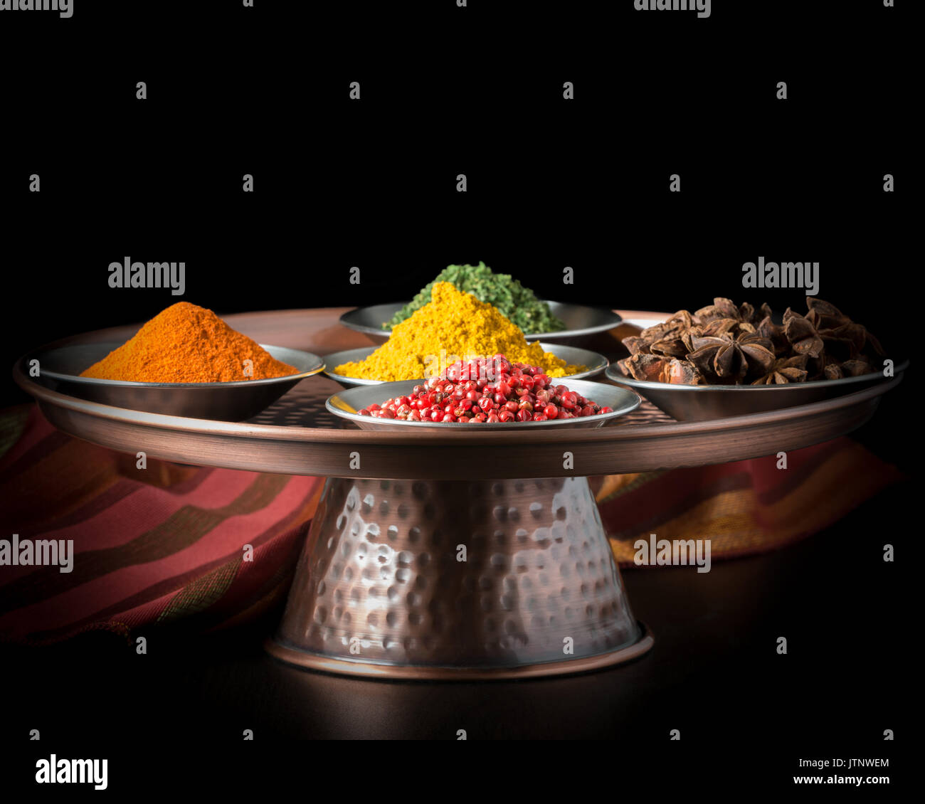 Colorata varietà di spezie su una presentazione di rame piatto. Foto Stock