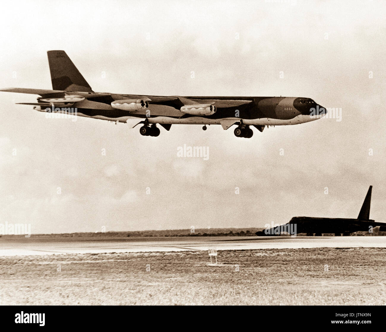 A B-52D Stratofortress aeromobile attende accanto alla pista come un B-52G approcci per lo sbarco dopo aver completato una missione i bombardamenti sul Nord Vietnam durante il funzionamento linebacker. Gli aerei sono dal Strategic Air Command. Foto Stock