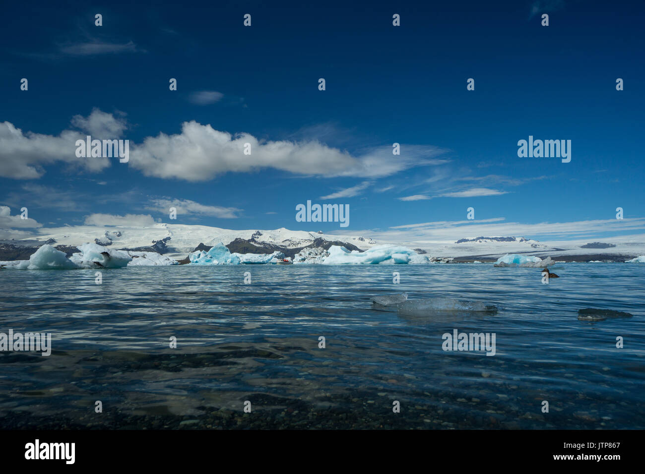 Islanda - chiare acque del lago glaciale con la barca lontano tra ice floes Foto Stock