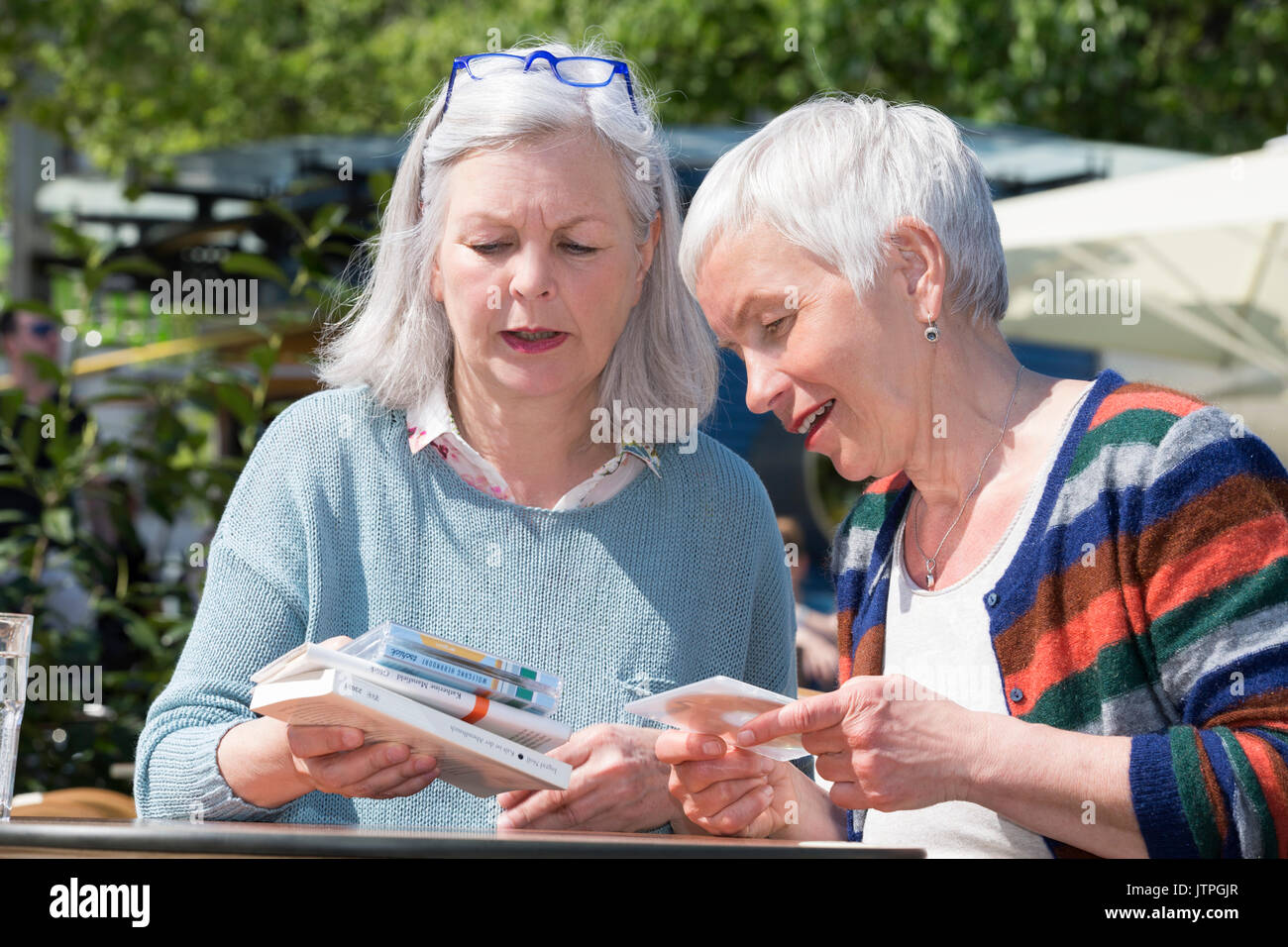 Due donna anziana scambio di libri e CD Foto Stock