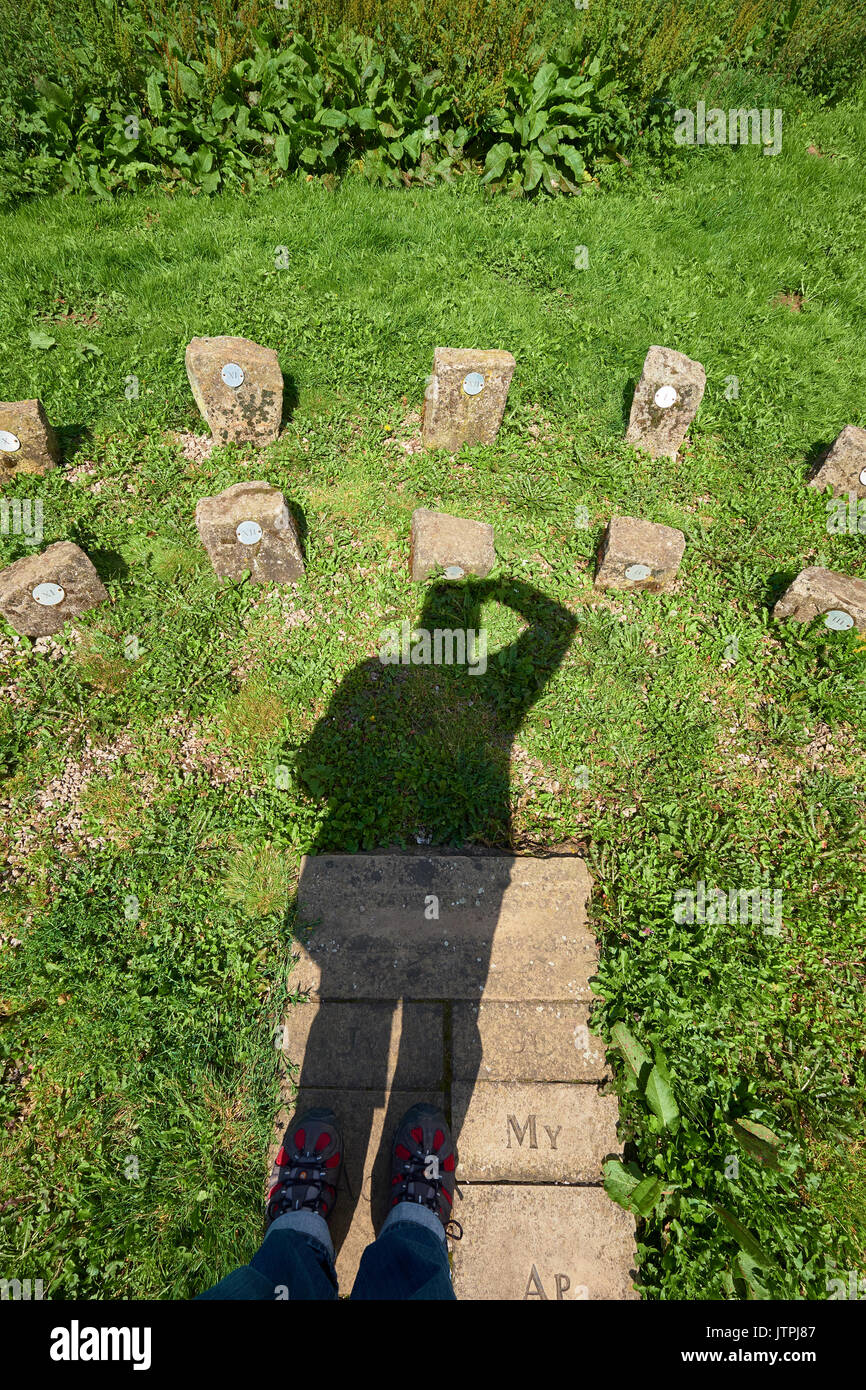 Ombra di un uomo adulto maschio agisce come lo gnomone su una meridiana umana. Ombra sul quadrante di pietre. Due file di pietre per l'ora legale DST. Foto Stock