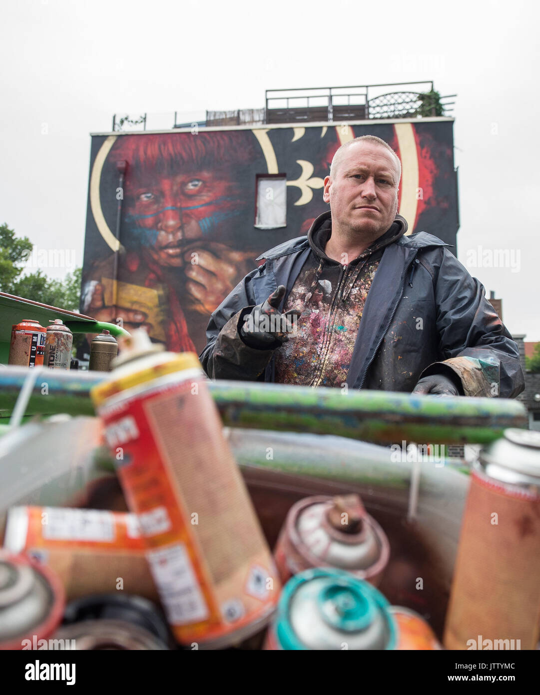 Hannover, Germania. 10 Ago, 2017. British artista Dale Grimshaw guardando la telecamera durante una street art project di Hannover, Germania, 10 agosto 2017. Un pezzo che egli è la visualizzazione tra 03 e 11 agosto sulla facciata di una casa può essere visto in background. Foto: Sila Stein/dpa/Alamy Live News Foto Stock