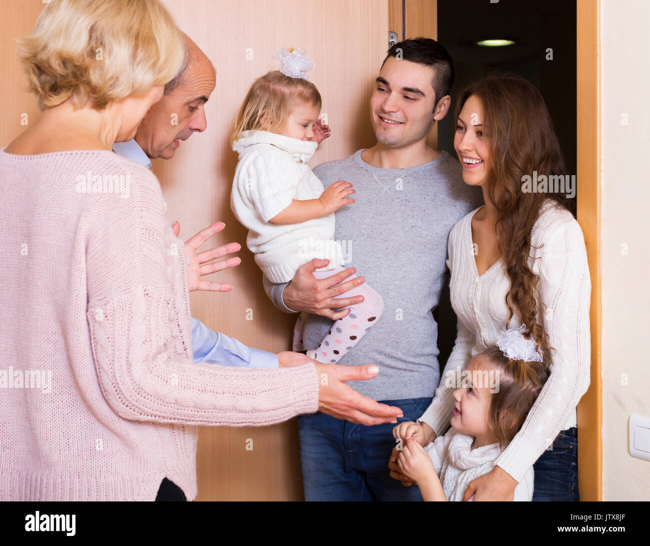 Positivo giovane famiglia con due figlie di visitare grand genitori Foto Stock