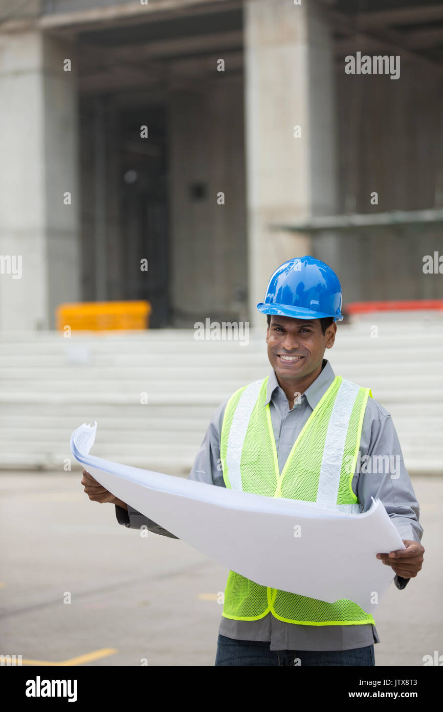 Indian construction manager o di un Architetto controllando il blueprint di piani di un edificio sito. Foto Stock