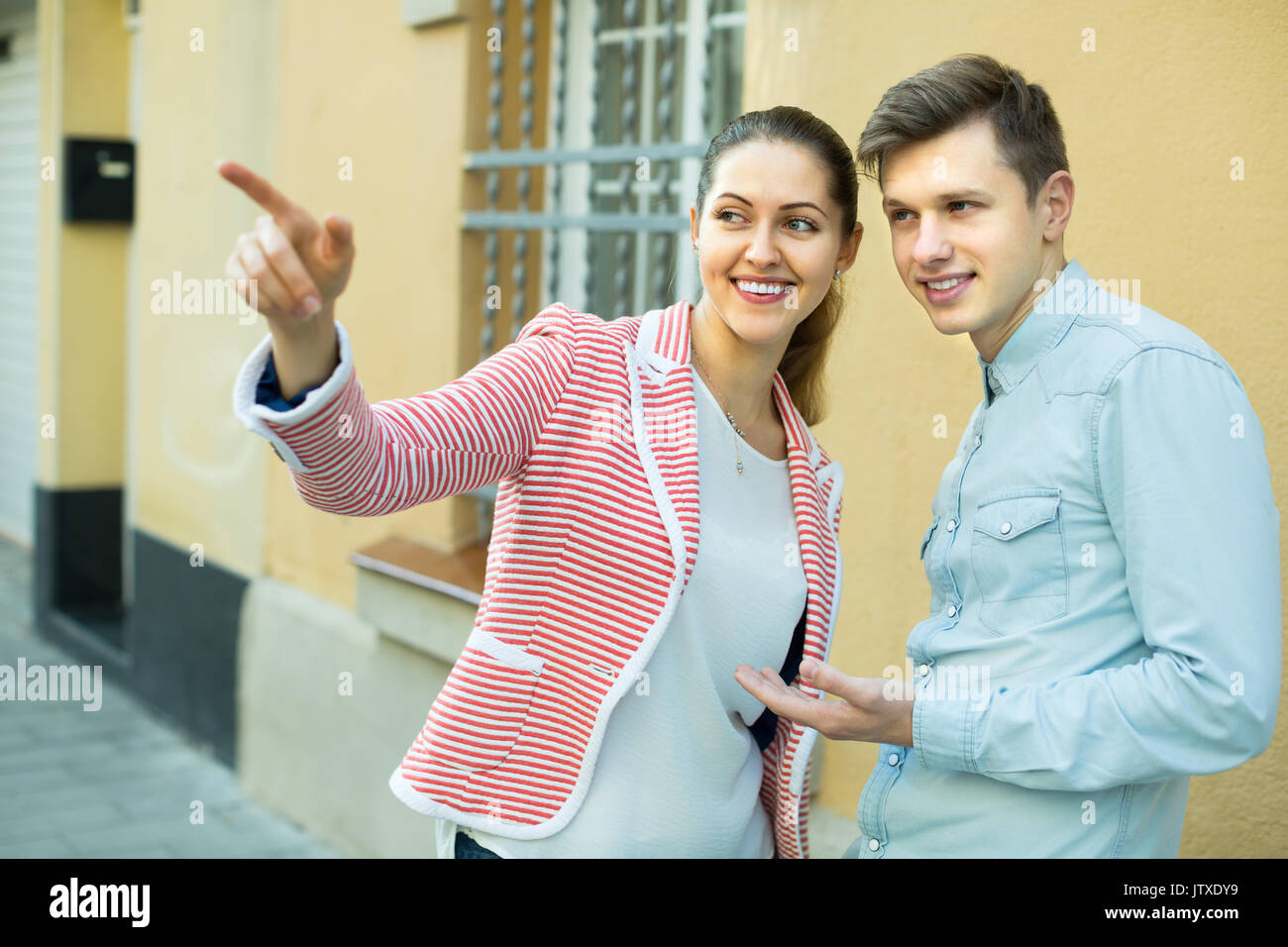 Friendly young brunette aiutando perso il turista maschio trovare modo Foto Stock