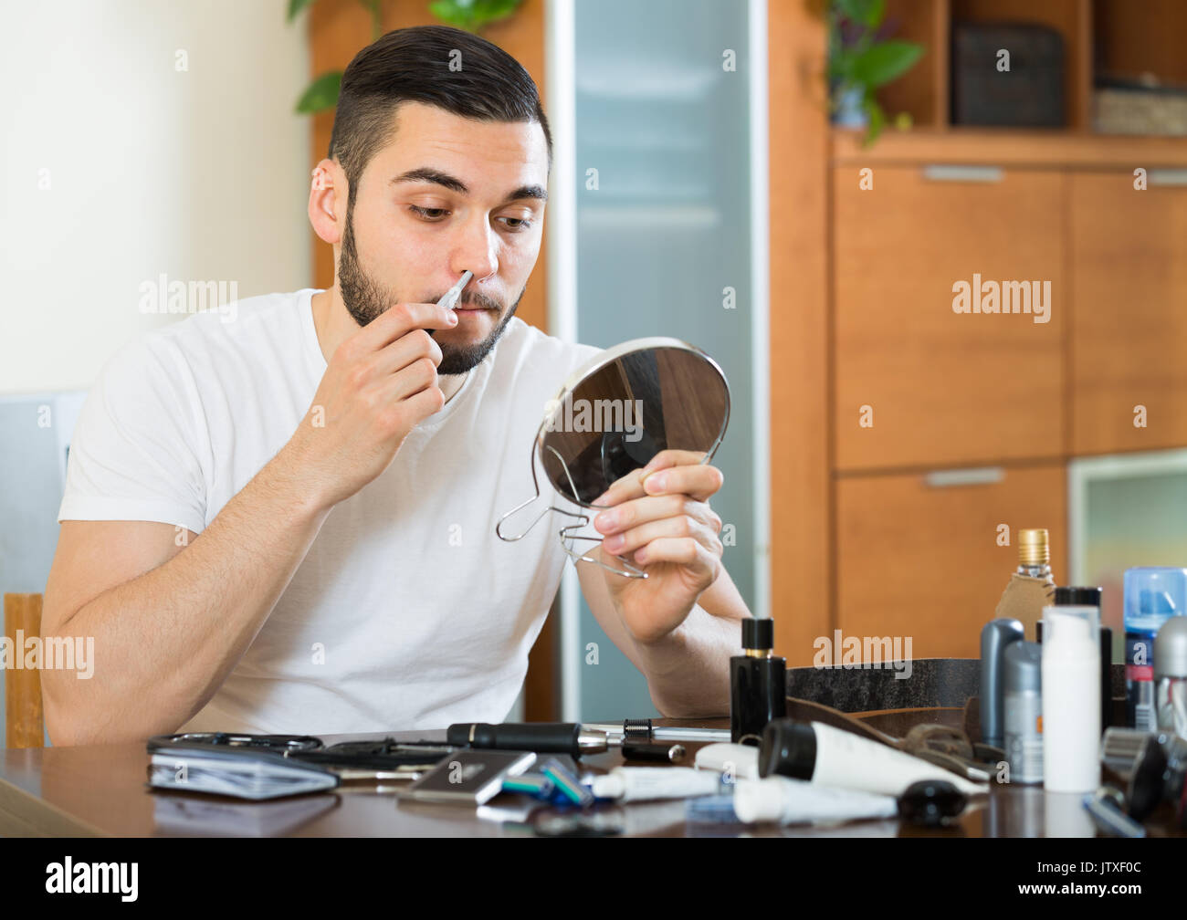 Guy 20 anni rimuovere i peli dal naso e orecchie con trimmer Foto Stock