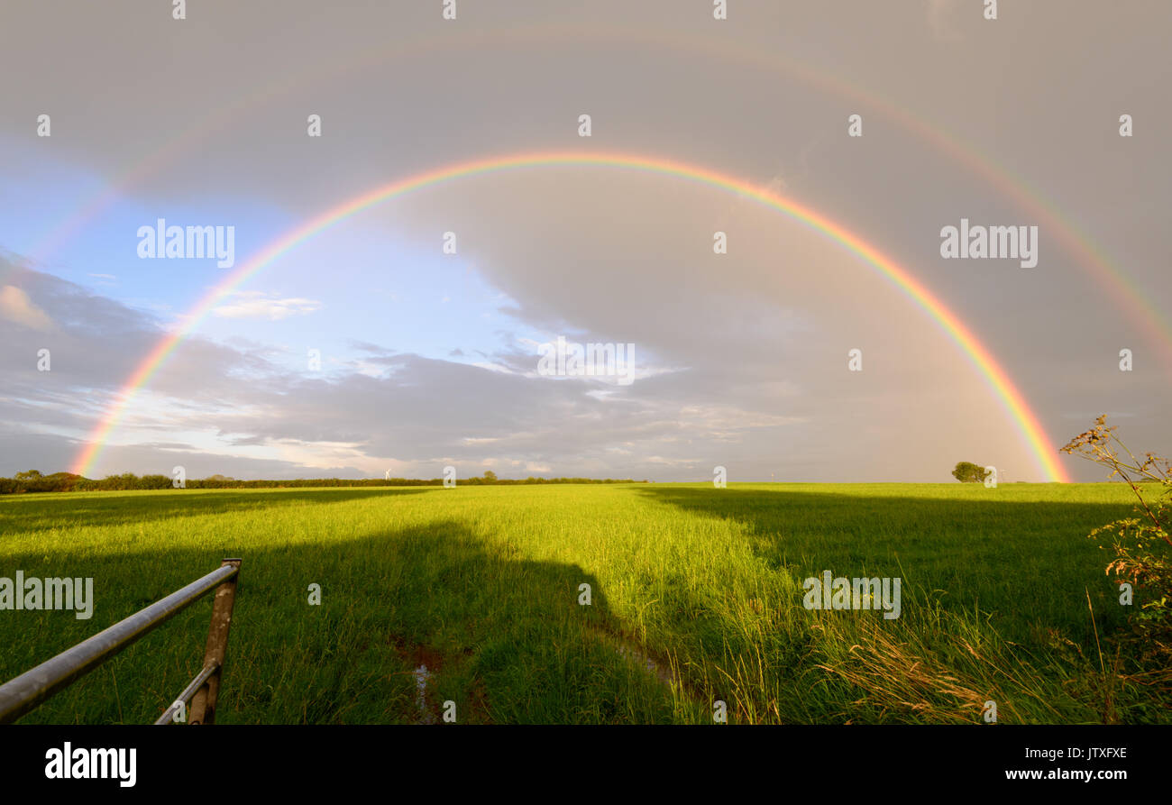 Doppio arcobaleno contro cieli grigi in mezzo alle docce intermittente. Foto Stock