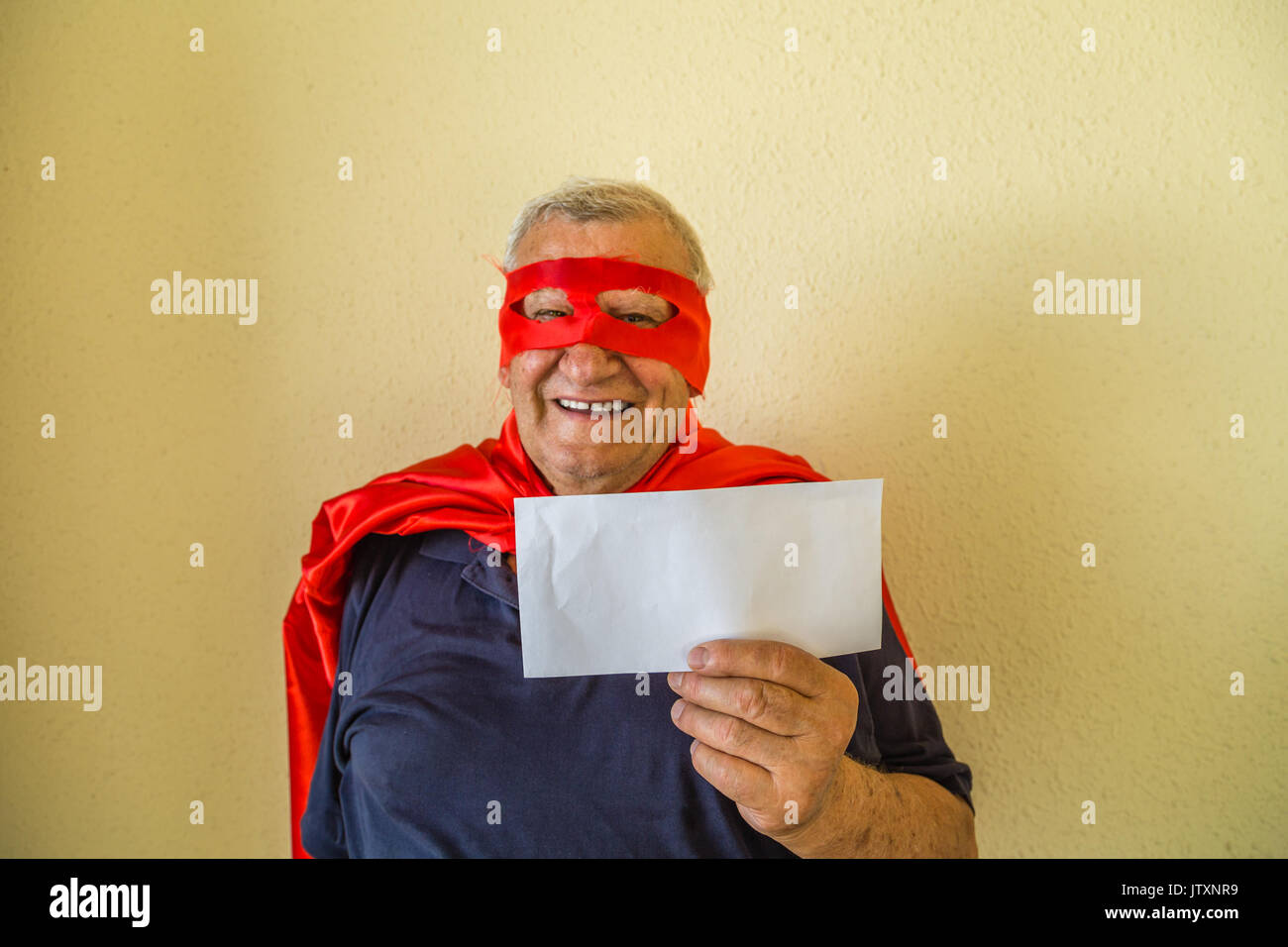 Il vecchio uomo in costume da supereroe holding busta bianca Foto Stock