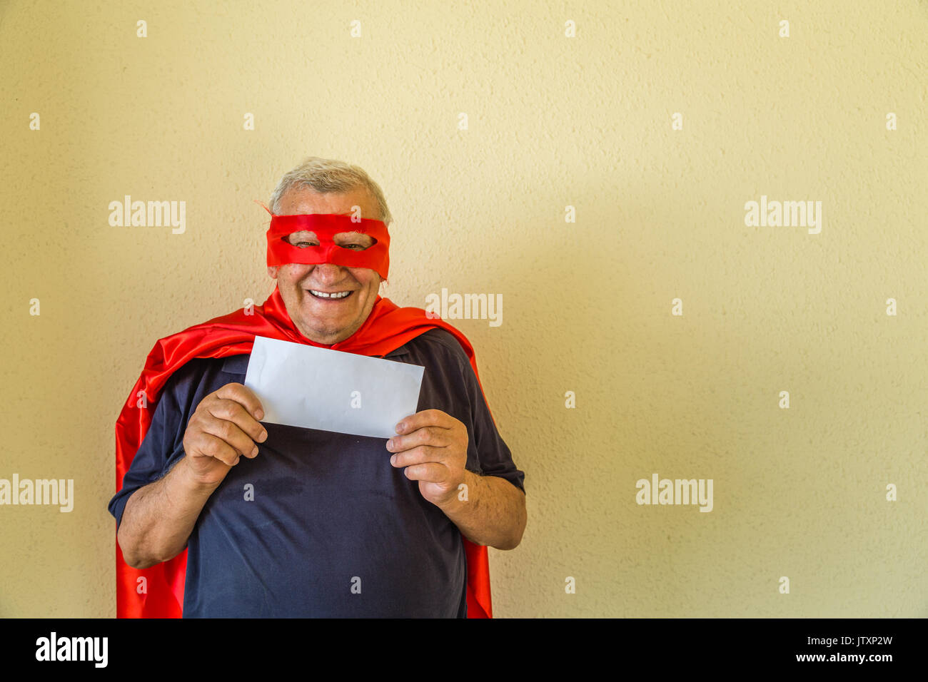 Il vecchio uomo in costume da supereroe holding busta bianca Foto Stock