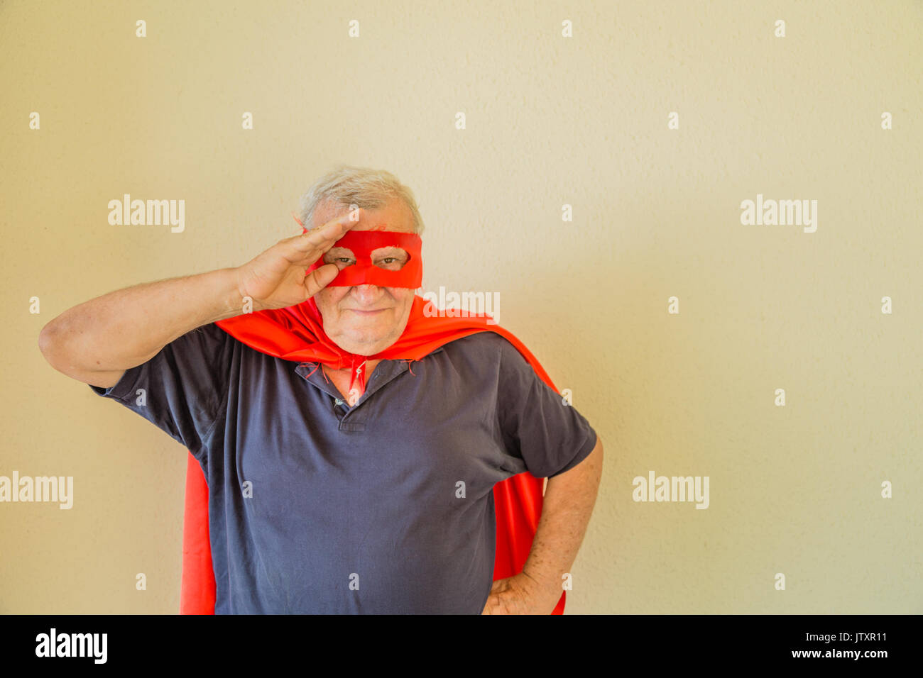 Saluto militare dal vecchio uomo giocando come supereroe Foto Stock