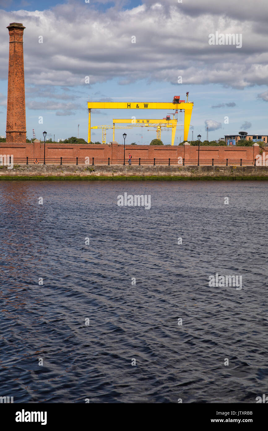 Belfast, una vista del vecchio cantiere navale, Harland e Wolff gru (Sansone e Golia) con il fiume Lagan, camino e mattoni rossi parete in primo piano Foto Stock