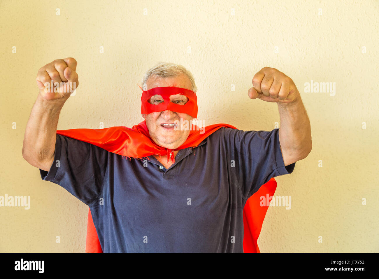 Il vecchio uomo vestito da supereroe maturo il sollevamento a suon di pugni Foto Stock