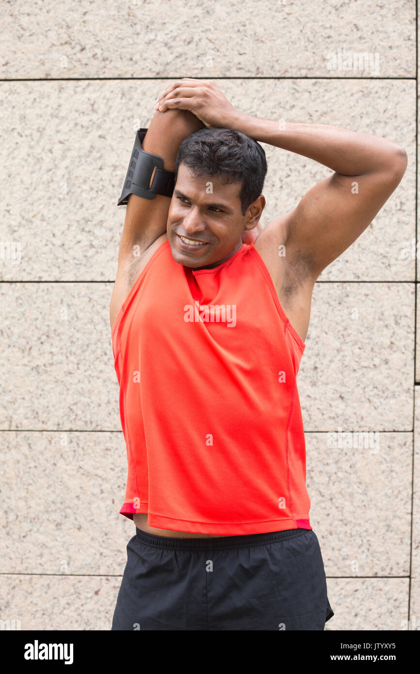 Atleta uomo indiano stretching all aperto in città urbana. Maschio di concetto di fitness. Foto Stock
