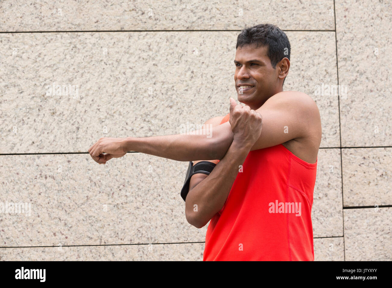 Atleta uomo indiano stretching all aperto in città urbana. Maschio di concetto di fitness. Foto Stock